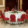 Chaises de banquet en tissu rouge et or autour d'une table de réception
