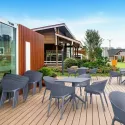 Fauteuil monobloc empilable en polypro gris foncé sur terrasse extérieure avec tables